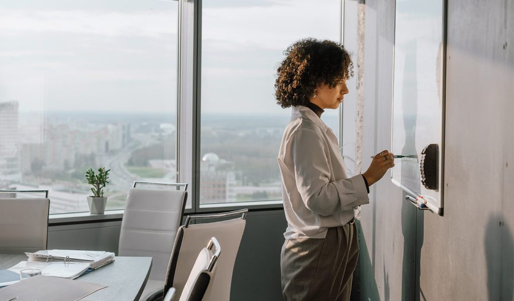 Person writing a book blurb outline on a whiteboard in an office