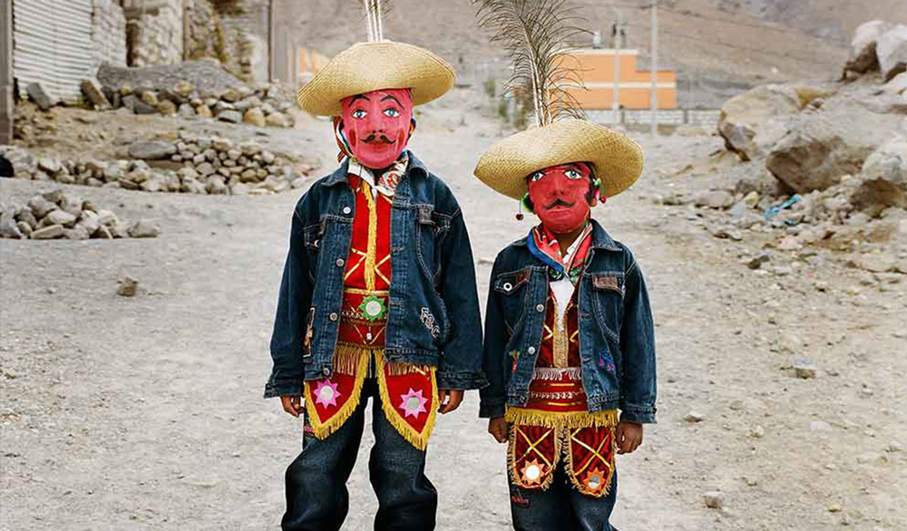 Portrait of two masked children dressed in traditional outfits.