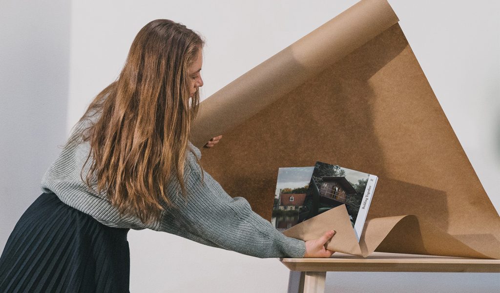 Person carefully packaging photography book, demonstrating books as marketing tools and promotional products for businesses