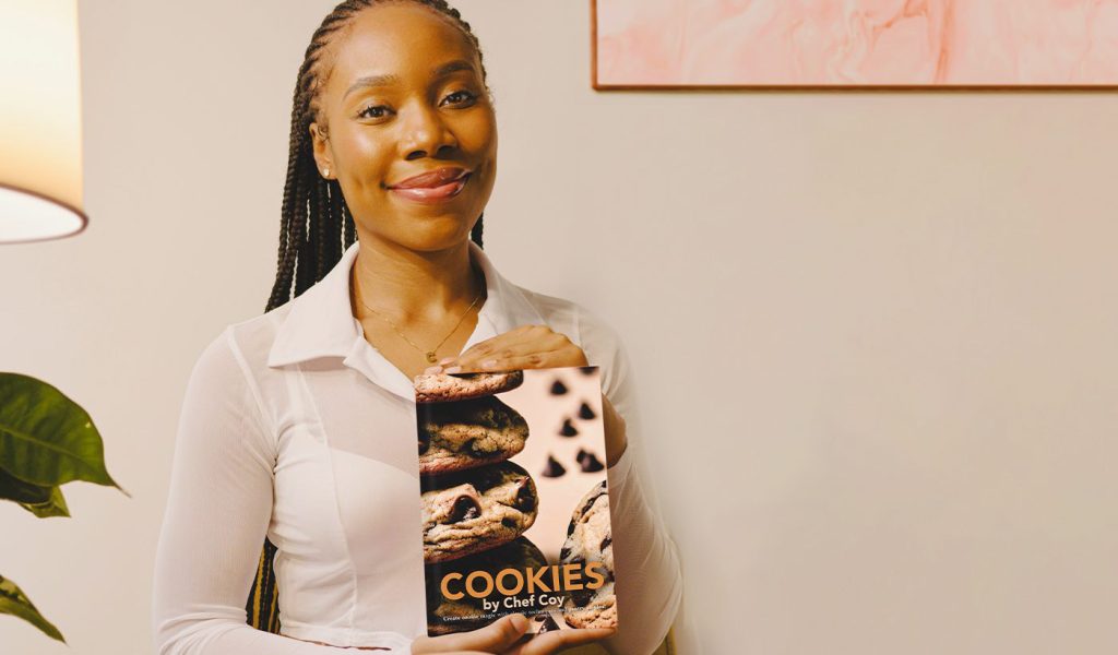 Chef Coy showcasing her self published cookbook, "Cookies by Chef Coy"