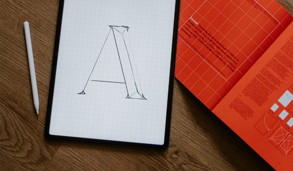 A digitally hand lettered capital "a" with a red book in the background.