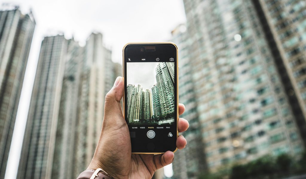 Cityscape from below being photographed on a phone. Photographer is using different perspectives