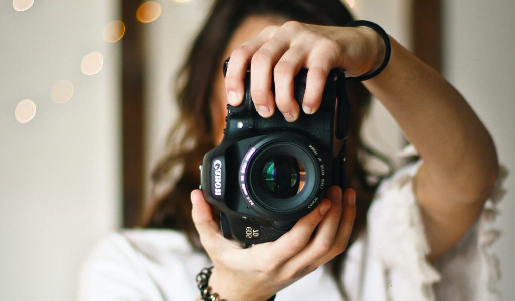 Photographer holding a Canon camera in front of their face