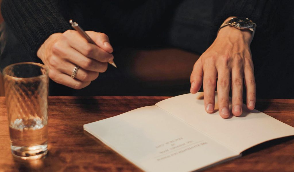 Person signing a book at a book signing at a bar