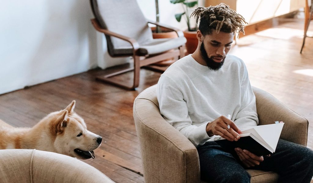 Person writing in a creative journal with a dog