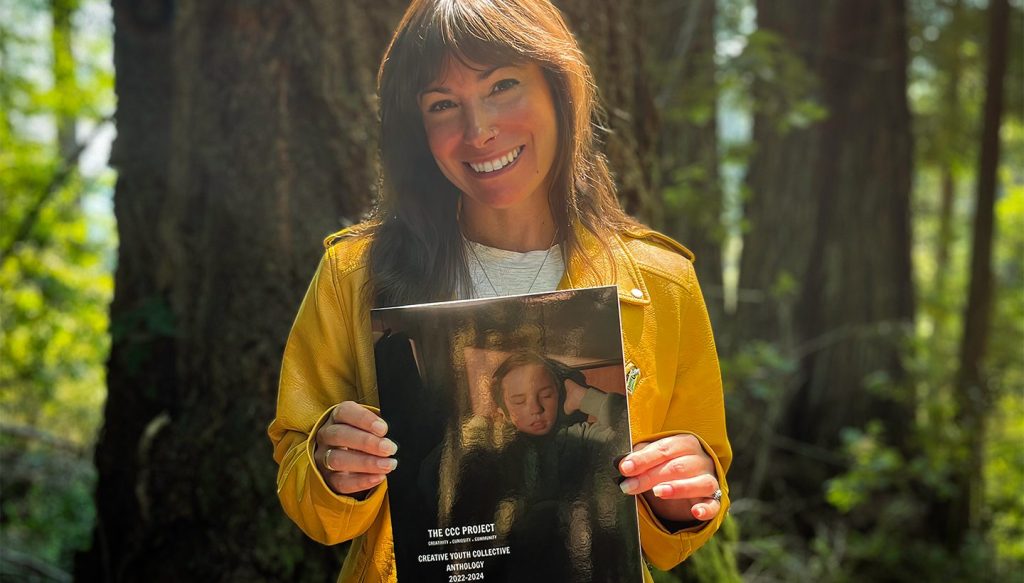 Kathryn Ian Gentzke holding up her self published book, The Creative Youth Collective Anthology